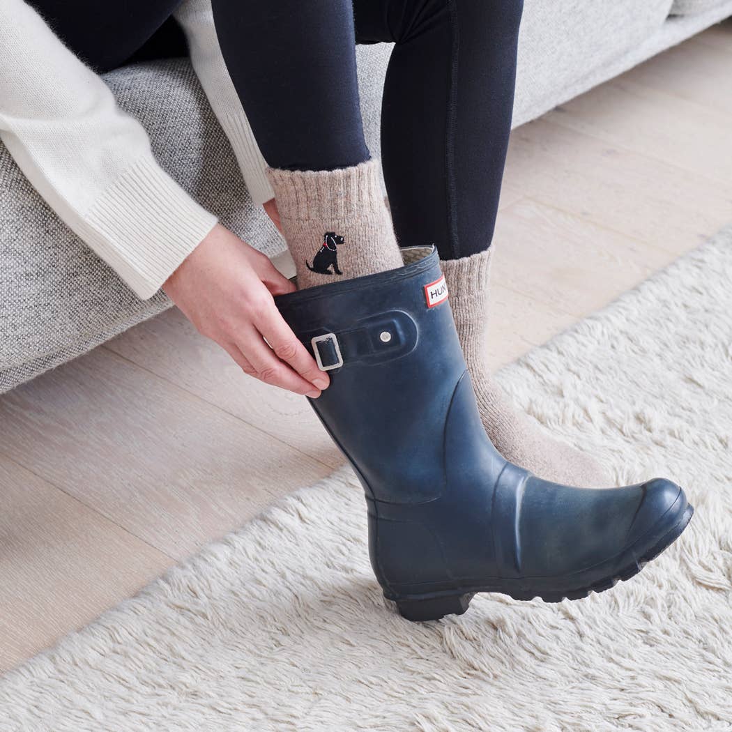 Person putting on a navy rain boot indoors