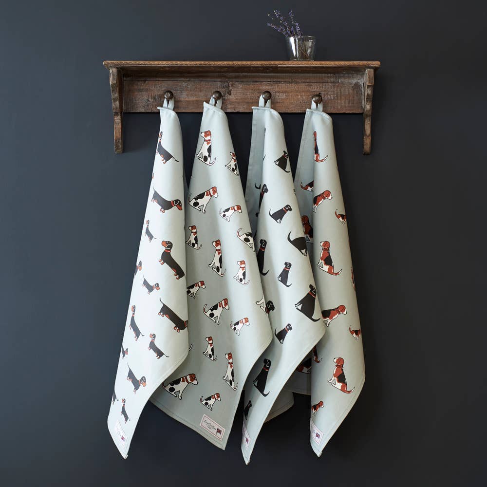 Three kitchen towels with a dachshund print hanging from a rustic wooden rack against a dark gray wall.