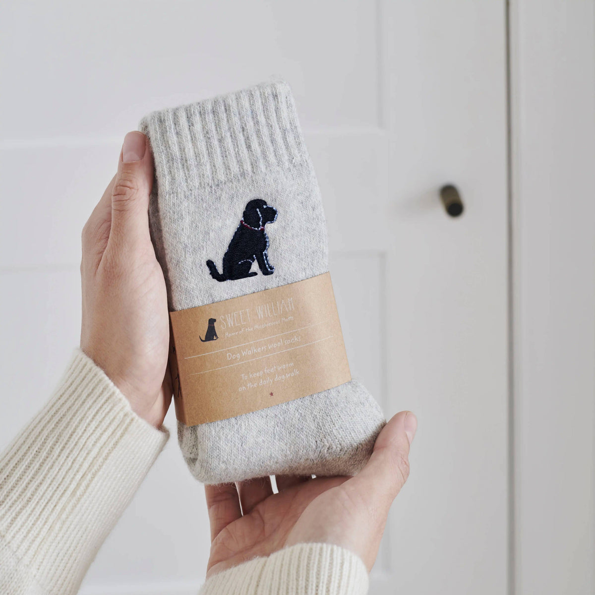 Gray sock with black dog design held by a hand against a light background