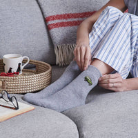 Person wearing gray socks with a black cat design on a couch