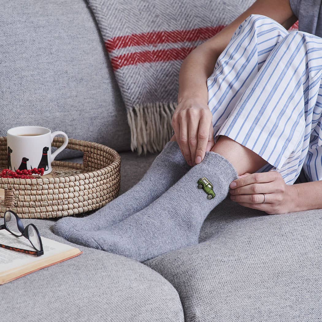 Person wearing gray socks with a black cat design on a couch