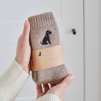 Brown sock with black dog design held by a hand against a light background