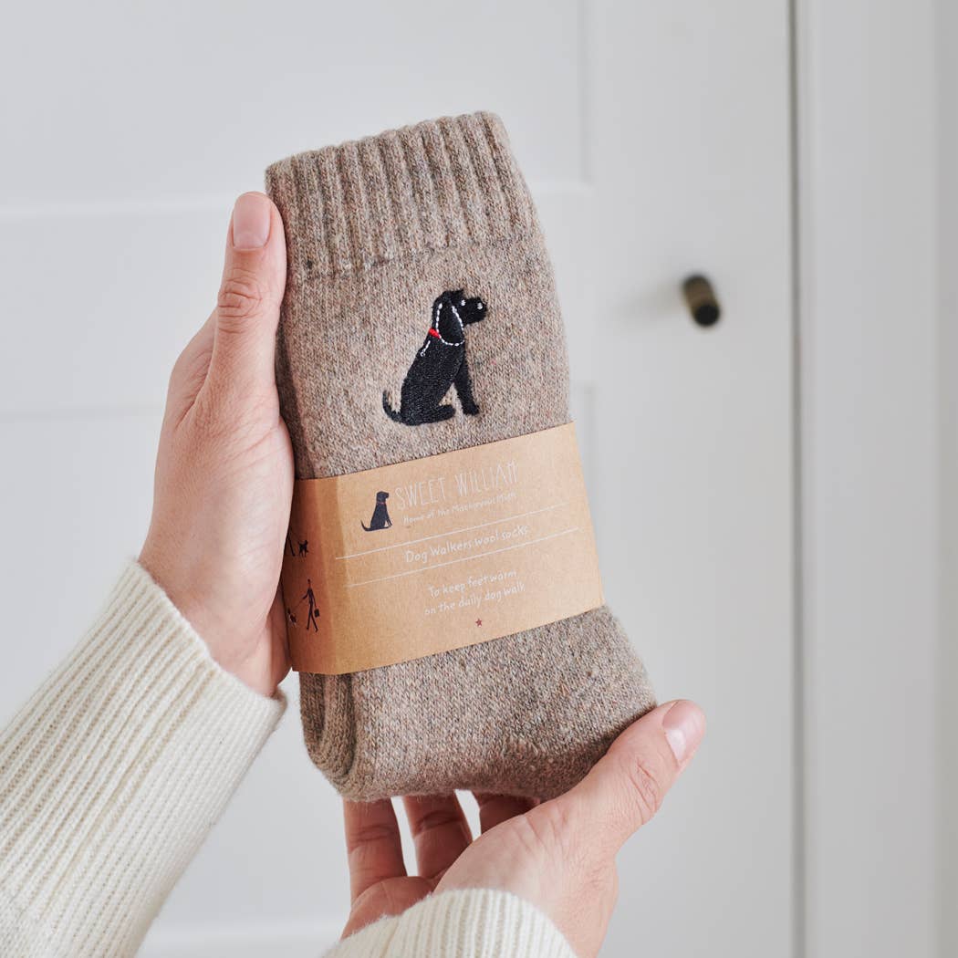 Brown sock with black dog design held by a hand against a light background