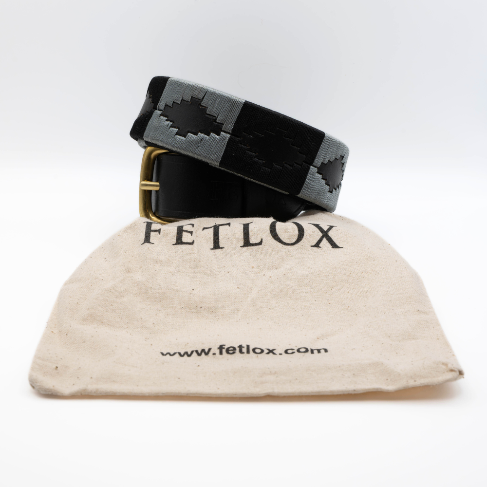 Black belt with a checkered pattern on a beige bag labeled 'Fetlox' on a white background