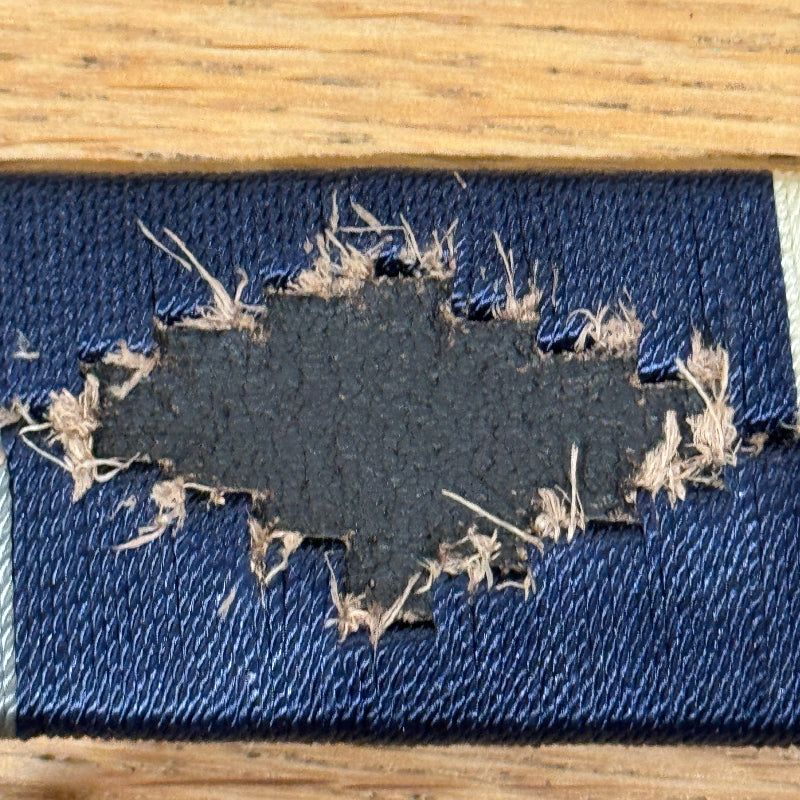 Close-up of a blue fabric patch with frayed edges on a wooden surface
