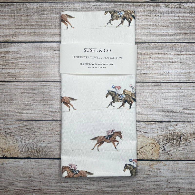 Tea towel with horse and jockey design on a wooden surface, featuring the brand 'SUSEL & CO'.