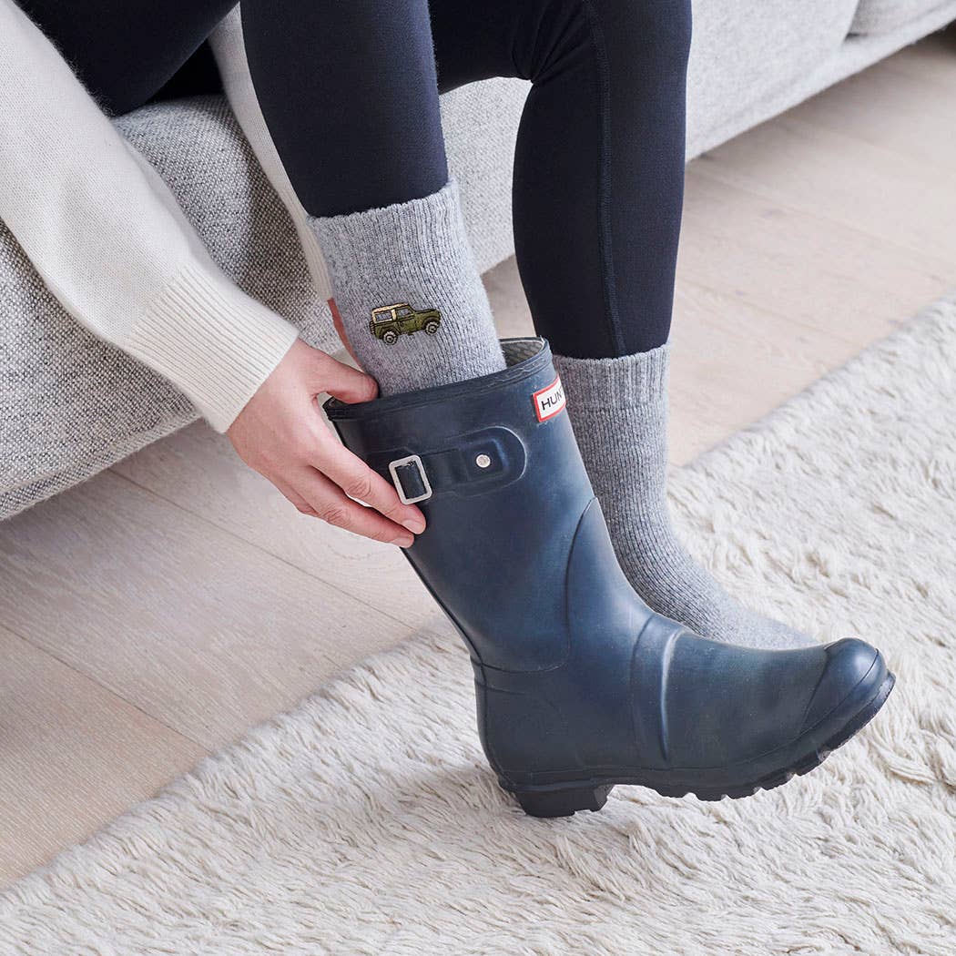 Person wearing a blue rain boot with a visible brand logo indoors.